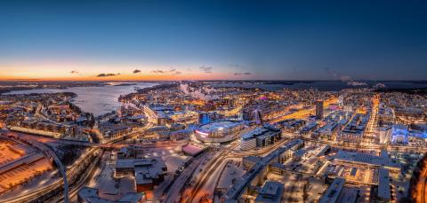 Dronella otettu kuva sinisellä hetkellä Nokia Areenasta ja kaupungista, jonka sadat tuikkivat valot valaisevat tiet ja talot.