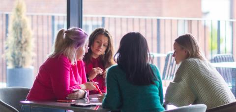 Neljä naista ideoimassa pöydän ääressä.