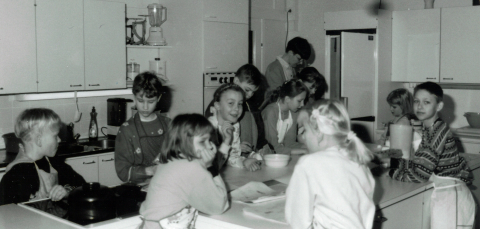 Lapset kokkaavat opetuskeittiössä. Taustalla on opettaja.