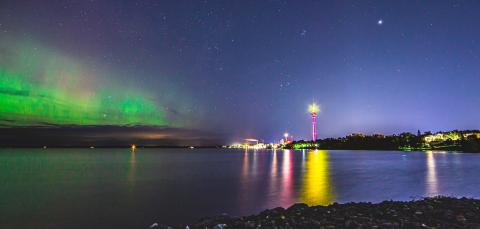 Öinen maisema Näsijärveltä, vihreitä revontulia taivaalla, Näsinneula ja kaupungin valot loistavat kaukaa.