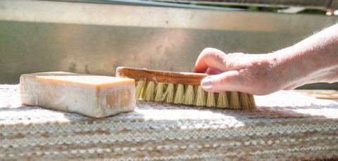 Pine soap, a washing brush and a rug in the rug washing site.