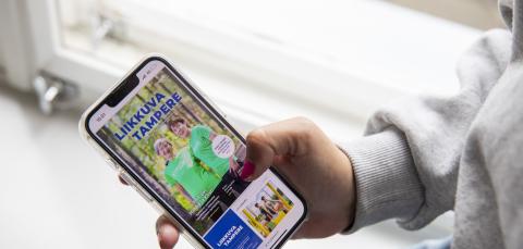 Henkilö lukee Liikkuva Tampere -lehteä älypuhelimella.