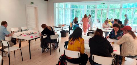 Osallistujat istuvat työpajassa pöytien ääressä ja kirjoittavat.