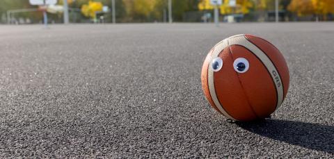 Koripallo, jolla on silmätarrat asfaltilla.