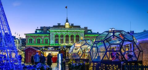 Glass igloos and stalls on the Christmas Market, with the illuminated Old City Hall in the background.