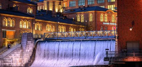 Tammerkosken vesiputous illalla valaistuna, taustalla vanhoja tehdasrakennuksia.