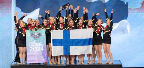 Palkintopallilla seisovia urheilijoita Suomen lippu edessä 