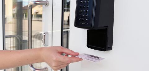 Asiakas pitää kirjastokorttia omatoimikirjaston lukijassa. 
