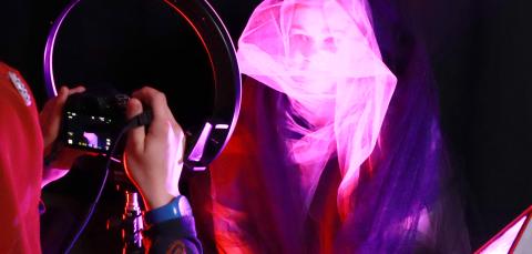 Kuva jossa kaksi nuorta valokuvaa toisiaan pimeässä huoneessa pinkissä valaistuksessa.