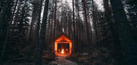 Retkeilijöitä iltahämissä nuotion ääressä Kintulammin kirkkokiven laavulla.