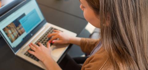 Nuori nainen kirjoittaa tietokoneella.