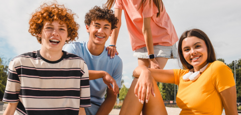 iloisia nuoria istumassa puistossa ja katsomassa kohti kameraa