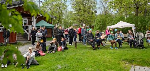 Iso joukko ihmisiä istuu ulkona odottamassa tapahtuman alkua. 