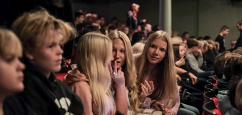 Kahdeksasluokkalaiset istuvat teatterin katsomossa ja juttelevat