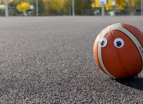 Koripallo, jolla on silmätarrat asfaltilla.