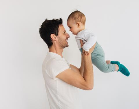 Isä nostaa vauvaa ja heillä on nenät vastakkain.