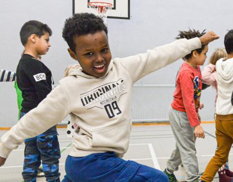 Lapsia tanssimassa vauhdikkaasti koulun liikuntasalissa.