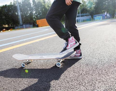 Henkilö pitää skeittilaudan päällä jalkaa.