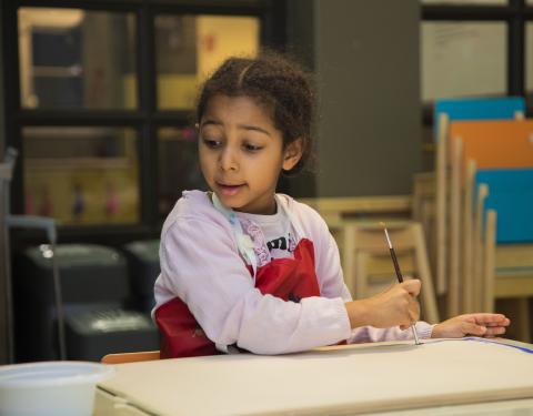 Lapsi maalaa vesivärisiveltimellä.