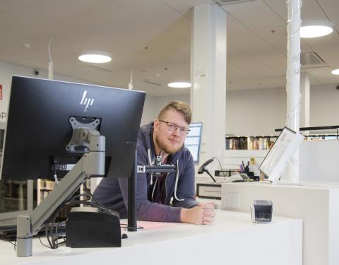 Kirjaston työntekijä asiakaspalvelutiskin ääressä.