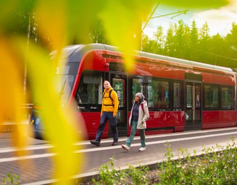 Two hikers walking next to a tram.