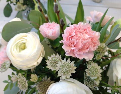 Lähikuva kukkakimpusta, jossa on neilikoita ja jaloleinikkejä.