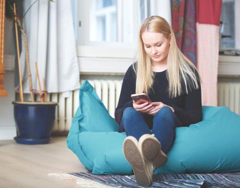 Nuori istuu säkkituolissa ja selaa puhelintaan.