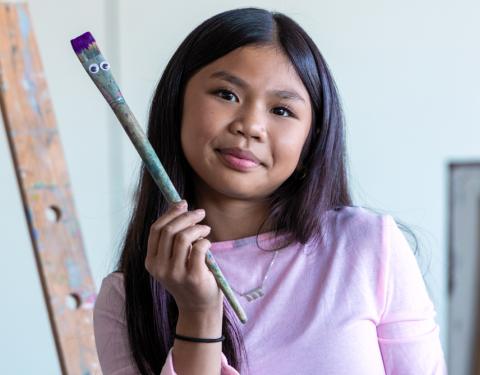 Nuorella on kädessään pensseli, jolla on silmät.