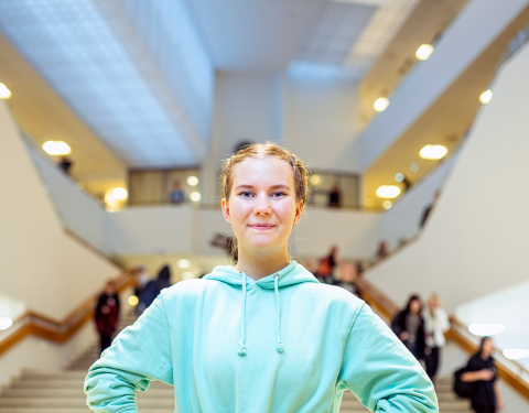Hymyilevä nuori seisoo Sampolan portaiden edessä kädet lanteilla.