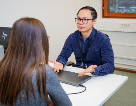 A person giving guidance to another person sitting by a table