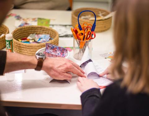 Kuvassa aikuinen ohjaa lasta askartelussa