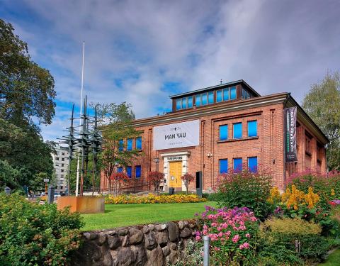 Punatiilinen taidemuseorakennus pilvisenä kesäpäivänä.