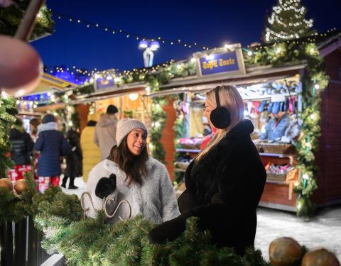 Kaksi henkilöä nauttimassa Joulutorin tunnelmasta pimeään aikaan.