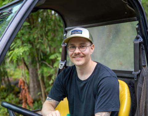 Henkilö istuu työkoneen kyydissä ja nojaa toisella kädellään rattiin.