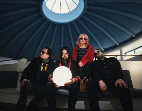 Nelihenkinen Risto-yhtye istuu aurinkolasit silmillä pääkirjasto Metson kupolin alla. Yksi jäsenistä pitelee käsissään valaistua palloa.