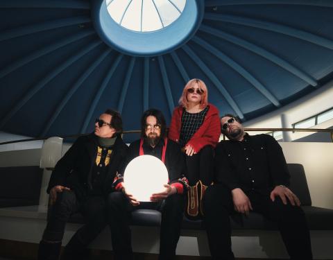 Nelihenkinen Risto-yhtye istuu aurinkolasit silmillä pääkirjasto Metson kupolin alla. Yksi jäsenistä pitelee käsissään valaistua palloa.