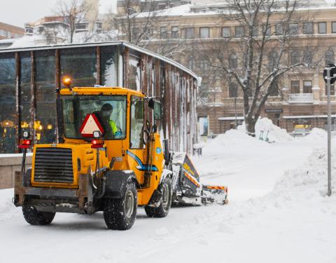 Auraustraktori lumitöissä keskustassa takaapäin kuvattuna.