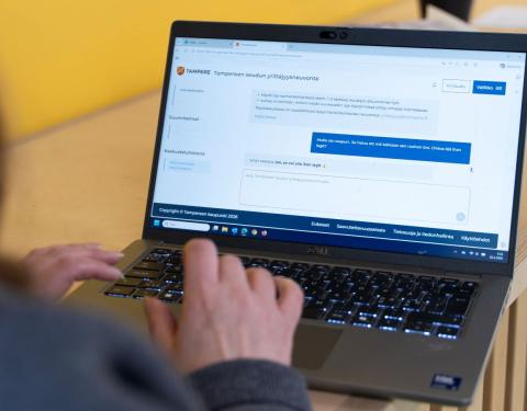 A person is studying the Entrepreneurship Advisory website on a laptop. The person is photographed from behind, with only a bit of hair, the right shoulder, and the hand visible. On the laptop screen, the webpage of the new service is displayed.