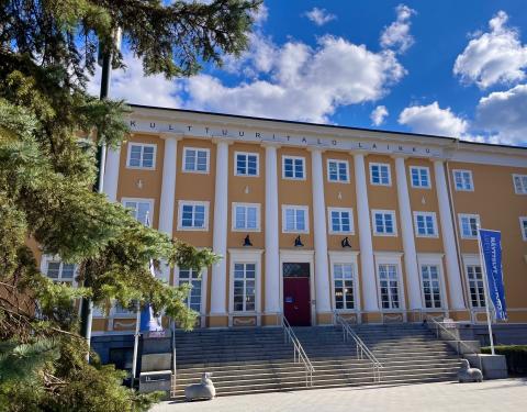 Kulttuuritalo Laikku keväisessä auringonpaisteessa, taustalla sininen taivas ja pilvenhattaroita.