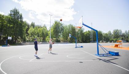 Kaksi miestä heittävät palloa koriin.