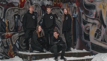 Viisi opiskelijaa graffititeoksen edessä.