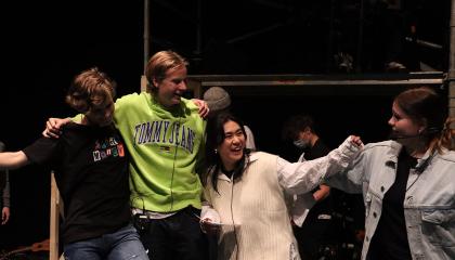 Neljä opiskelijaa pitävät toisiaan hartioista kiinni.