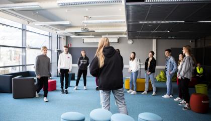 Opiskelijat seisovat ringissä, yksi on edessä.