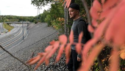 Henkilöä seisoo rinteen reunalla. Edessä punaisia pihlajanlehtiä.