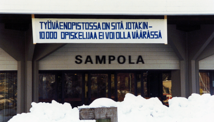 Sampolan edessä roikkuu mainoslakana, jossa lukee työväenopistossa on sitä jotakin.