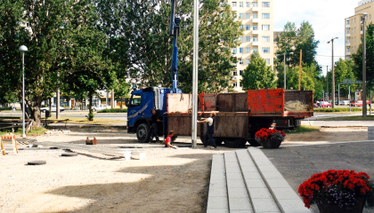 Rakennustyömaa, jonka taustalla on lava-auto ja edessä betoniportaat..