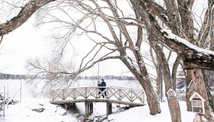 Pariskunta puisella sillalla Arboretumissa talvella.