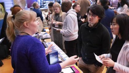Kaupungin työntekijä keskustelee kahden asukkaan kanssa. Taustalla näkyy paljon muistakin asukkaita.