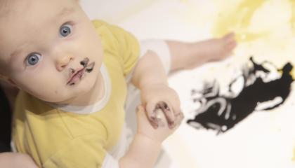 Vauva maalaa mustalla värillä taideteosta.