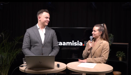 Mies kannettavan tietokoneen kanssa ja nainen mikrofoni kädessä juttelevat.